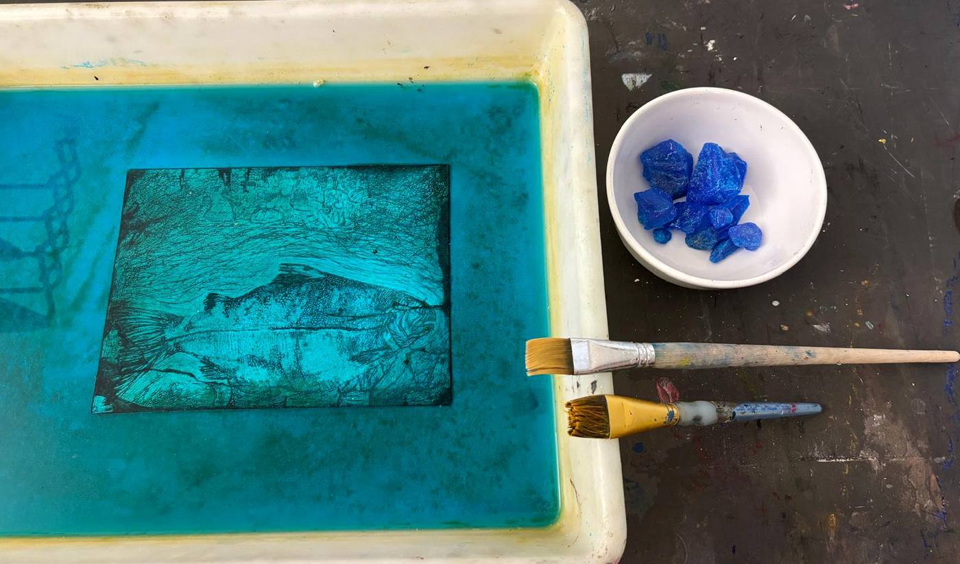 An etched plate in a blue copper sulfate bath, with blue crystals and brushes